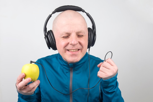 Un homme heureux portant des écouteurs portables pleine taille écoute de la musique à l'aide d'un lecteur Apple