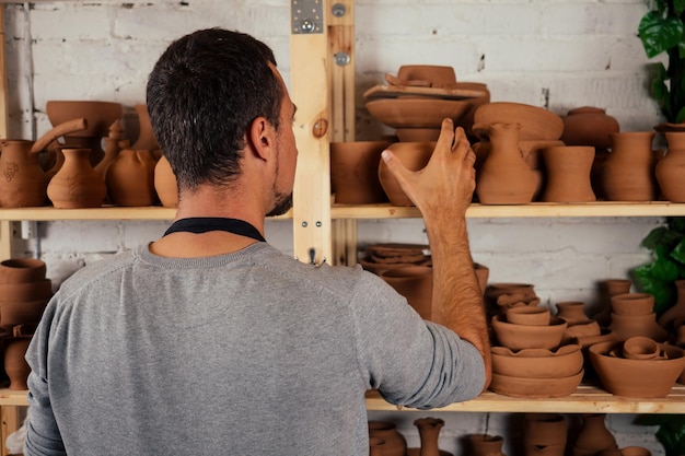 Homme heureux professionnel de potier travaillant avec de l'argile brune en atelier. homme d'affaires artiste commerce pot artisanal