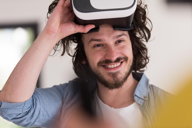 un homme heureux qui acquiert de l'expérience en utilisant des lunettes de réalité virtuelle avec casque VR à la maison