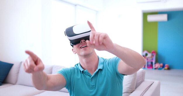 un homme heureux qui acquiert de l'expérience en utilisant des lunettes de réalité virtuelle avec casque VR à la maison