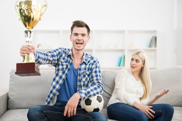 L'homme heureux regarde un football et fait un geste près de la femme sur le canapé