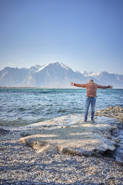 un homme heureux saute en l'air au lac suisse