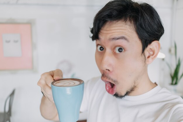 Un homme heureux savoure son café et se selfie avec sa tasse de café