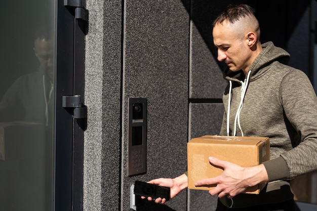 Un homme heureux sonne l'intercom avec une caméra dans l'entrée.