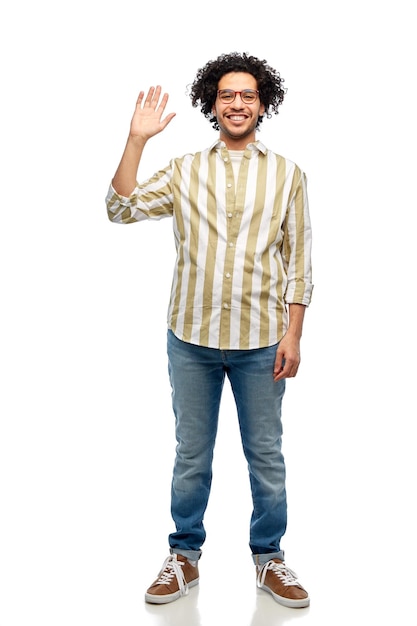 Un homme heureux et souriant avec des lunettes agitant la main.