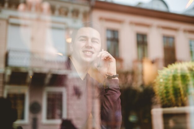 L'homme heureux téléphone au-dessus de la fenêtre