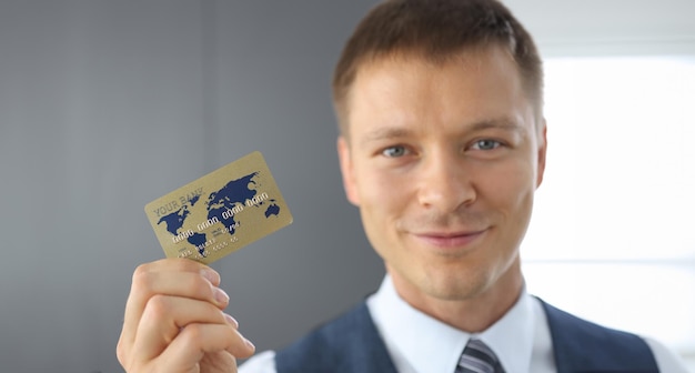 Photo un homme heureux tient une carte en plastique à la main.