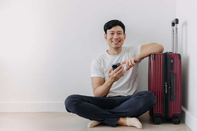 Un homme heureux utilisant une application de voyage sur son téléphone en attendant son transport