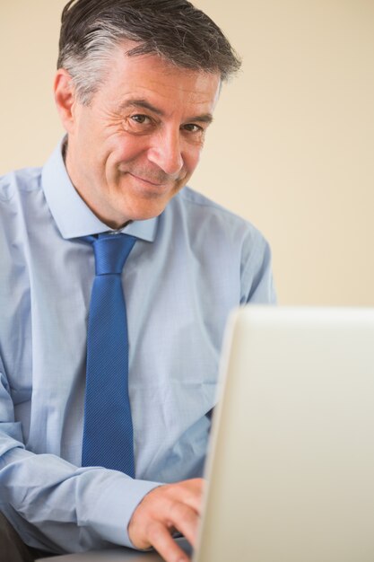 Homme heureux en utilisant un ordinateur portable assis sur le lit