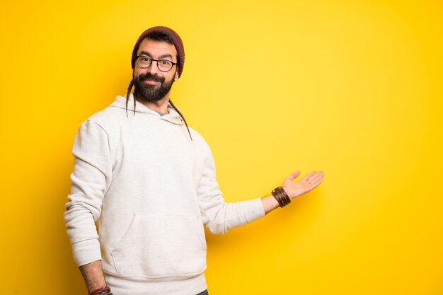 Homme hippie avec des dreadlocks pointant en arrière et présentant un produit