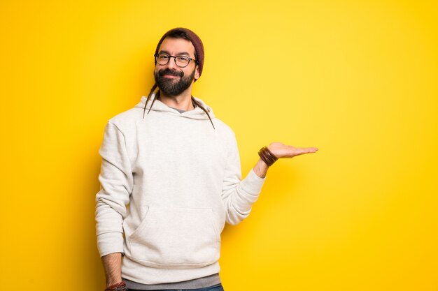 Homme hippie avec des dreadlocks tenant une surface imaginaire sur la paume pour insérer une annonce