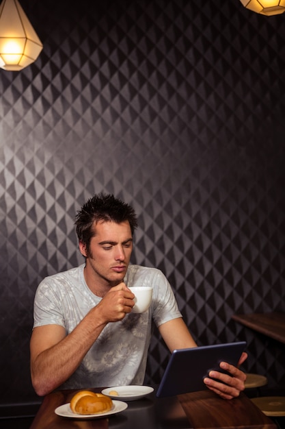 Homme de hipster à l'aide de tablette avec café et pâtisserie