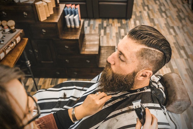 Homme hipster au salon de coiffure se faire couper la barbe et les cheveux