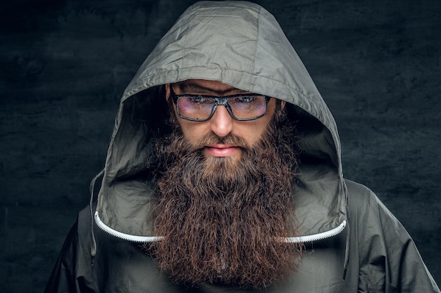 Homme hipster barbu brutal dans une hotte sur fond gris.