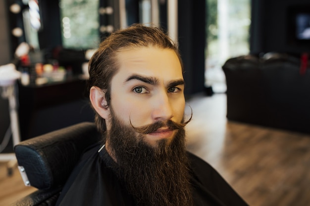 Homme hipster barbu dans un salon de coiffure tendance élégant.