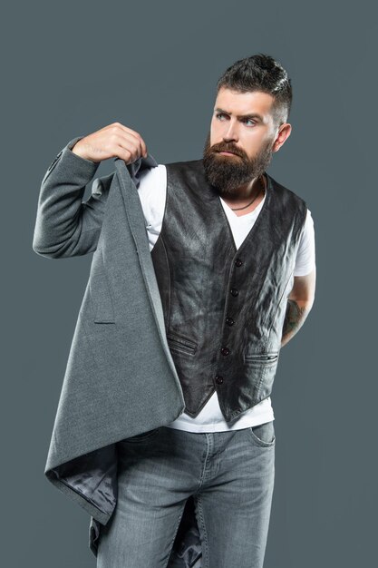 Homme hipster barbu portant une veste sur fond gris