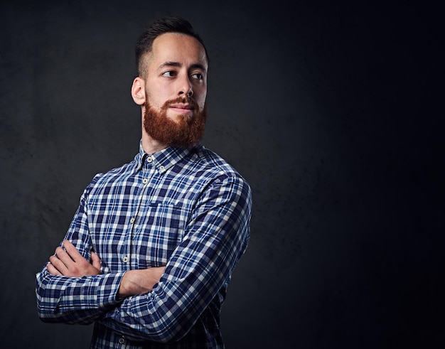 Homme hipster barbu rousse réfléchie avec les bras croisés, vêtu d'une chemise polaire bleue.