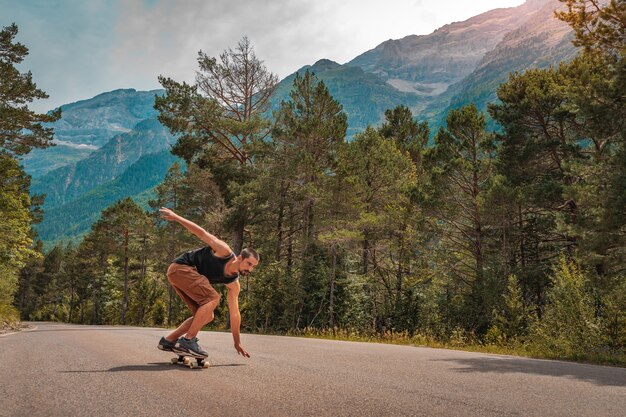 Photo homme de hipster long embarquement sur une route de montagne sinueuse