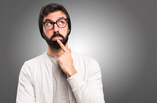 Homme de hipster pensant sur fond gris