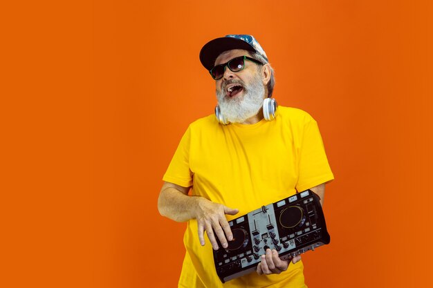 Homme de hipster senior utilisant des appareils, des gadgets sur fond orange