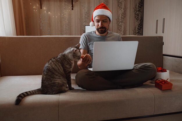 Un homme hipster avec une tasse rouge assis à la maison au moment de Noël