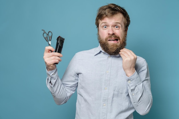 Un homme hirsute est alarmé parce qu'il doit se couper avec des ciseaux et une tondeuse pendant la quarantaine