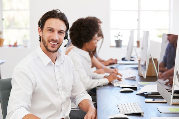 Homme hispanique avec casque souriant à la caméra dans un bureau