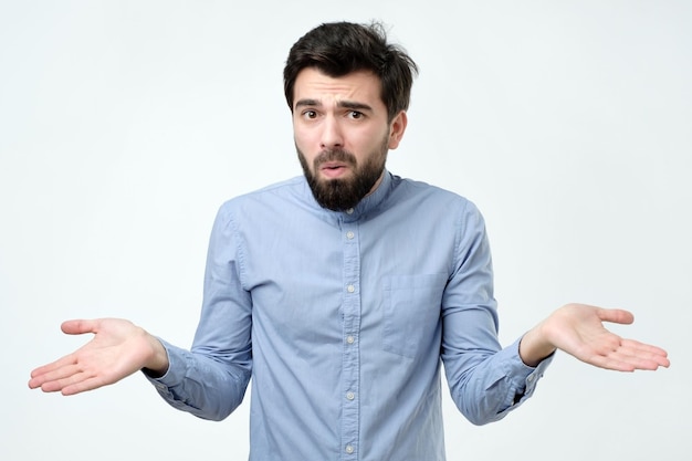 Un homme hispanique en chemise bleue lève les mains en signe d'incrédulité