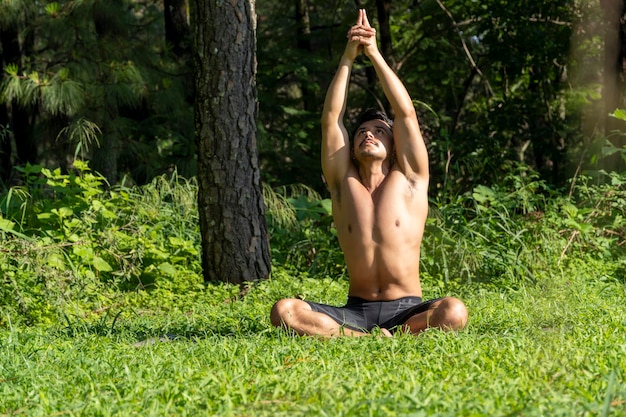 Homme hispanique et latin méditant au milieu d'une forêt recevant des rayons de soleil peau brune mexique