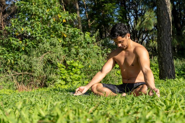 Homme hispanique et latin méditant au milieu d'une forêt recevant des rayons de soleil peau brune mexique