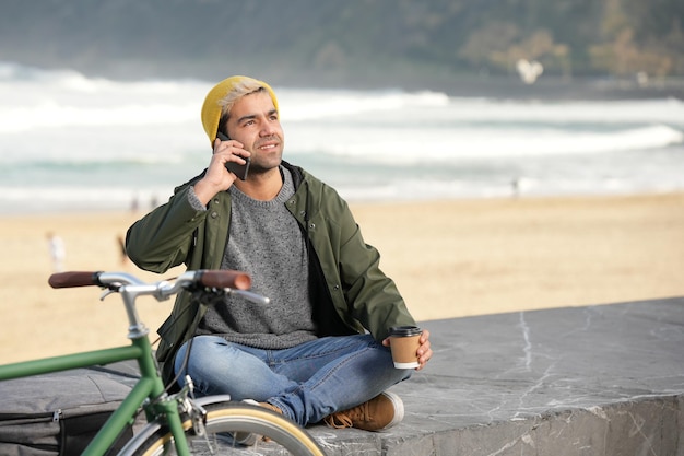 Homme hispanique parlant au téléphone et se relaxant à côté d'un vélo