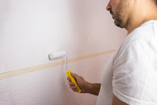 Homme hispanique peignant le mur avec un rouleau à peinture