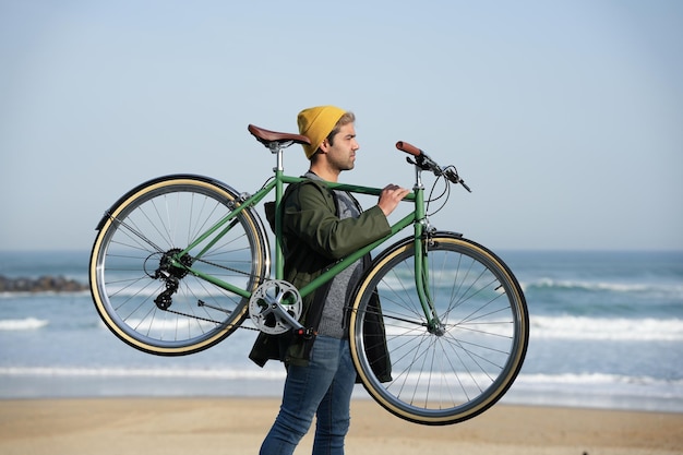 Homme hispanique portant un vélo classique sur les épaules à la côte