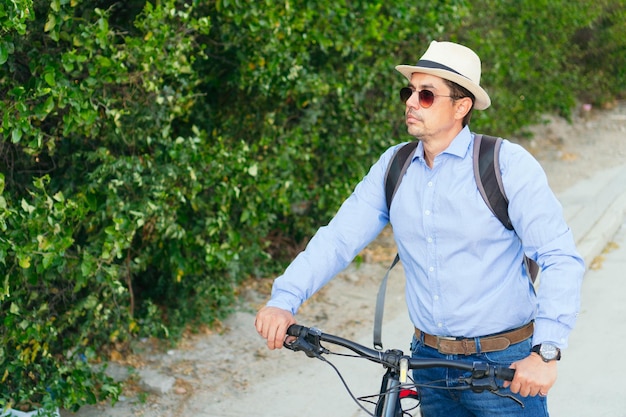 Un homme hispanique promenait son vélo dans la ville. Il regarde sur le côté