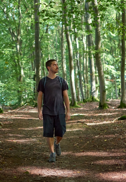 Un homme hispanique avec un sac à dos marchant dans la forêt