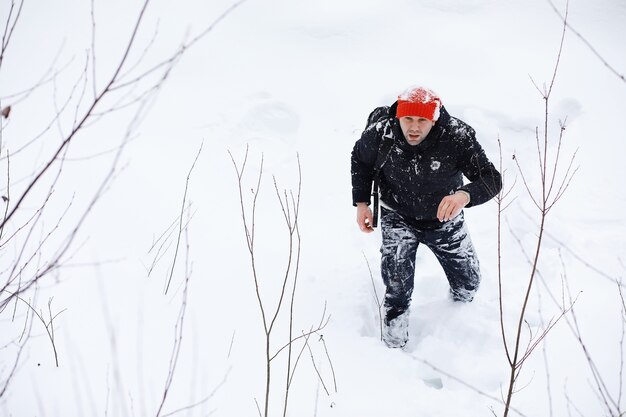 Un homme en hiver dans la forêt. Un touriste avec un sac à dos traverse les bois en hiver. Ascension hivernale.