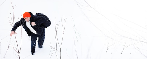 Un homme en hiver dans la forêt. Un touriste avec un sac à dos traverse les bois en hiver. Ascension hivernale.