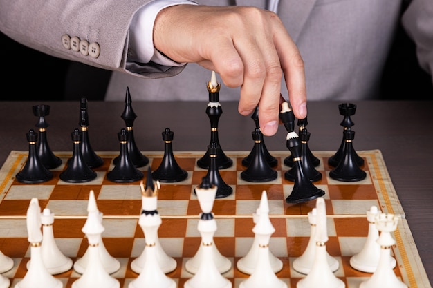 Un homme, un homme d'affaires joue aux échecs, fait un mouvement une pièce noire
