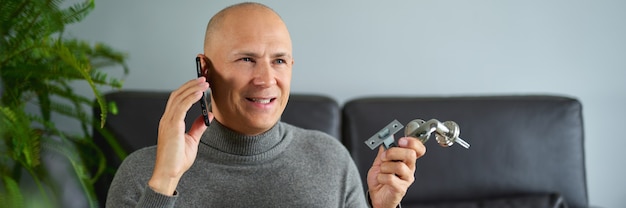 L'homme d'homme tient des garnitures de meubles et parle au téléphone portable au canapé.