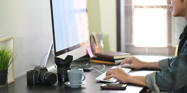 L'homme D'image Recadrée Utilise Un Ordinateur Au Bureau Entouré De Divers équipements