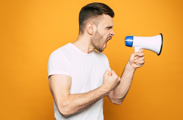 Un homme avec un imitateur émotionnel tient un mégaphone dans sa main et crie à quelqu'un avec l'aide de celui-ci