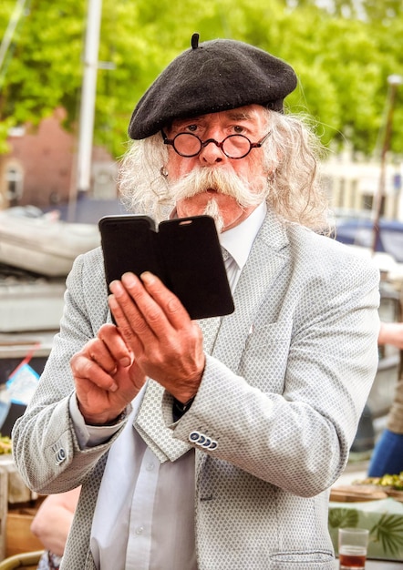 Un homme imposant avec une moustache dans un béret lunettes cravate et téléphone dans un café de la rue aux Pays-Bas