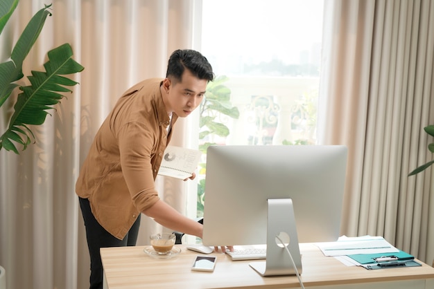 L'homme indépendant asiatique pense et travaille sur son ordinateur. Concept de travaux créatifs indépendants.