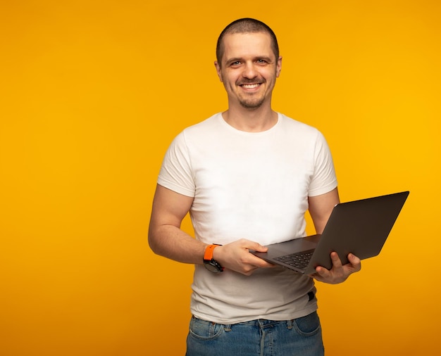 Homme indépendant en chemise blanche tenant un développeur informatique pour ordinateur portable sur fond orange