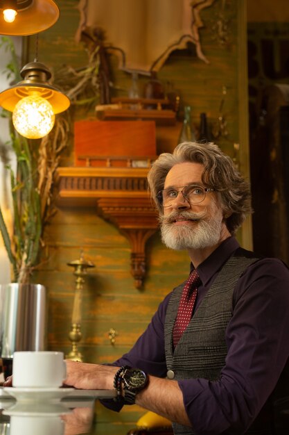 Homme indépendant. Homme réfléchi assis dans le café avec une tasse de café et travaillant sur son nouveau projet.