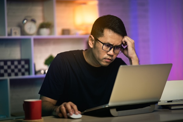 Homme indépendant sérieux et occupé à travailler avec un ordinateur portable sur la table, concept de travail à domicile