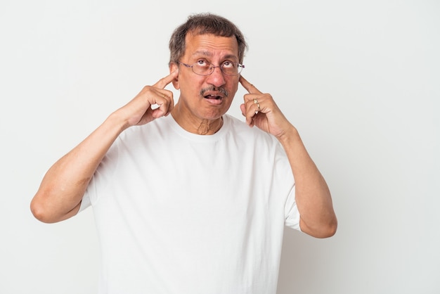 Homme indien d'âge moyen isolé sur fond blanc couvrant les oreilles avec les doigts, stressé et désespéré par une ambiance bruyante.