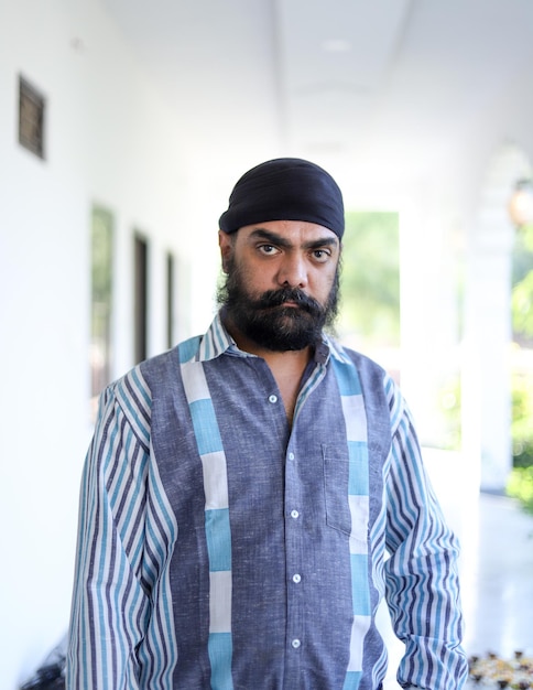 Homme indien d'âge moyen portant un turban sur la tête et posant avec une expression faciale sérieuse