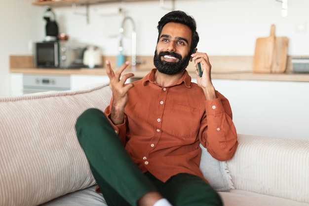 Homme indien barbu parlant au téléphone appréciant la conversation à la maison