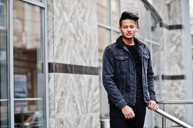 Homme indien beau et à la mode en veste de jeans noir posé en plein air